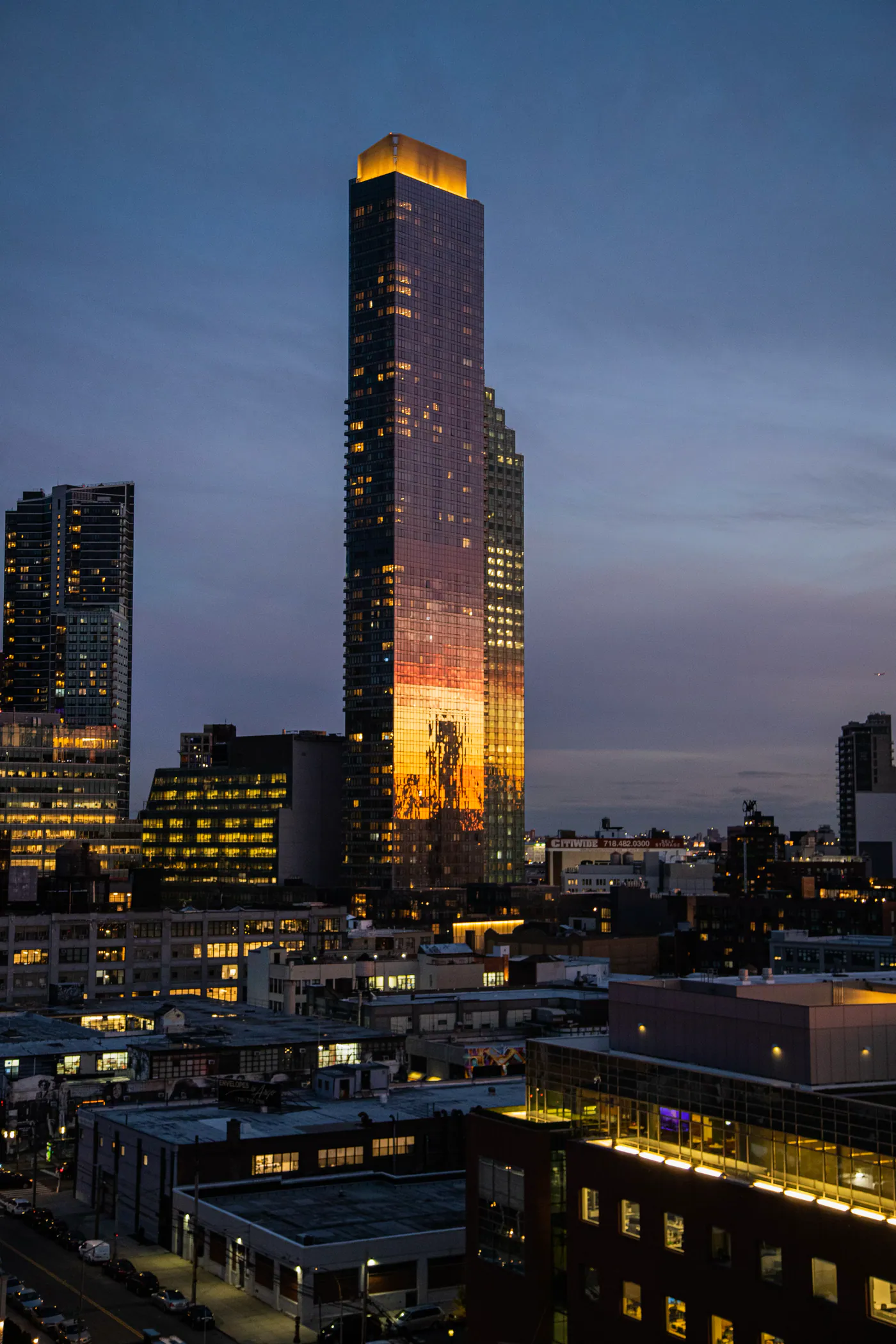 Hochhaus in der Dämmerung, dessen Fassade im letzten Licht orange leuchtet